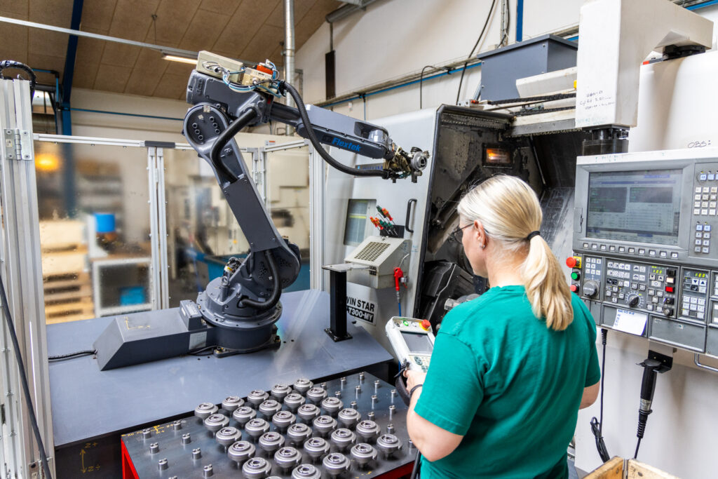 Operatør styrer industrirobot ved CNC-maskine